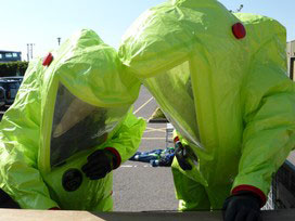 A team wearing protective clothing assessing the source of a leak involving an acid